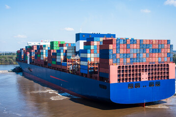 A massive cargo ship loaded with containers maneuvers carefully during docking operations at the...
