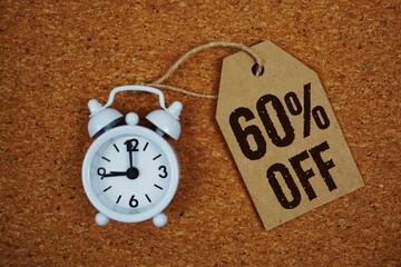 Sale 60% Off text on price tag with alarm clock on cork board background