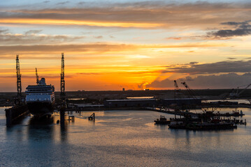 Fototapeta premium The rising sun casts a warm, golden glow over Freeport, Bahamas, illuminating the coastline and repair shipyard at the horizon. 