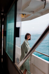 A young woman stands on the deck of a cruise ship and looks at the setting sun, close-up...