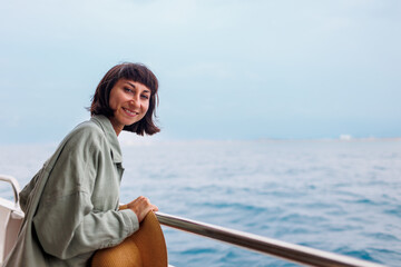 young woman stands on the deck of a cruise ship and enjoys the journey. happy woman. woman on a yacht on vacation, vacation and travel.