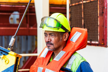 A lone sailor, equipped with a life jacket and helmet, stands alert and ready for action during the...