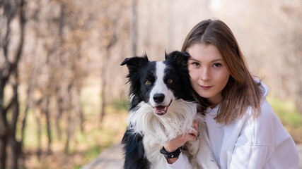 Caucasian woman hugging border collie in autumn park. Portrait of a girl with a dog.