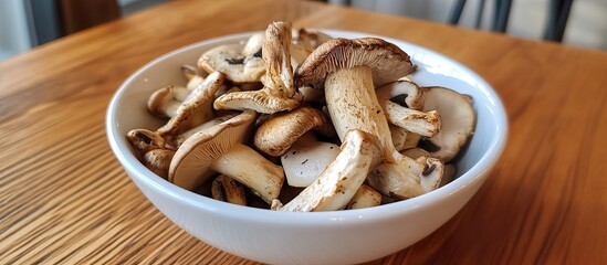 A bowl of mixed mushrooms, including shiitake and oyster, on a wooden table.