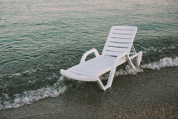 Obraz premium White Beach Lounger by the Edge of the Sea at Sunset