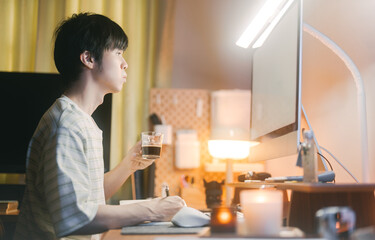 Asian man holding coffee drink freelance lifestyles working from home LED ambient warming desk light