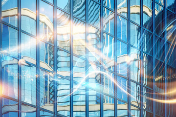 A modern glass building reflects a glowing, abstract pattern of light, creating an illusion of movement.