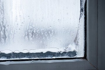 A detailed closeup of a window that is covered in condensation and raindrops, evoking a warm and...