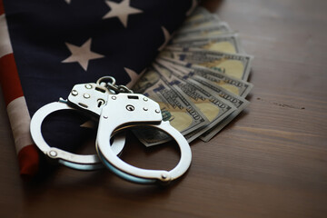 Handcuffs on American Flag with Cash: Crime, Law Enforcement, and Financial Crimes Concept