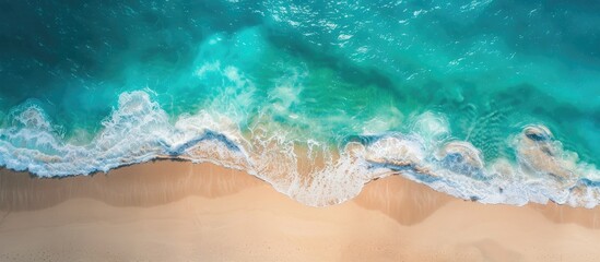 Fototapeta premium A stunning aerial view shows a serene beach with turquoise waters captured by a drone providing copy space for your text