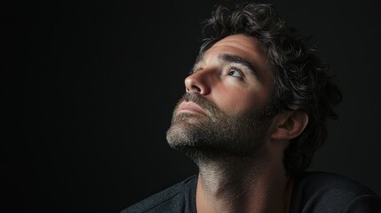 Fototapeta premium A dramatic studio portrait of a man gazing upward, creating a sense of aspiration and hope