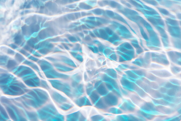 Blue water with ripples on the surface. Defocus blurred transparent blue colored clear calm water surface texture with splashes and bubbles. Water waves with shining pattern texture background.