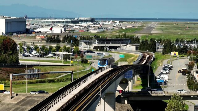 A SkyTrain Glides along an Elevated Track, with Planes and Runways in the Background Close to YVR in British Columbia, Canada - Static Shot