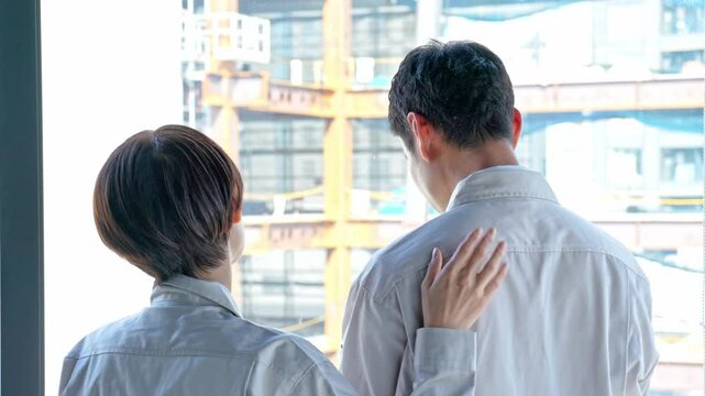 男性を励ます作業着を着た女性