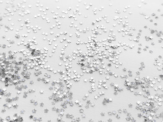 Shimmering silver star confetti on white background for festive occasions