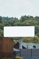 Empty roadside billboard with blank space and trees in background