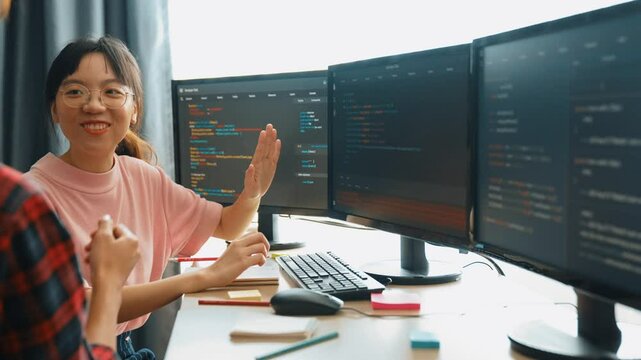 Slow motion back end software developer engineer for computer programming working together on debugging writing computing code, solving complex algorithms display on monitor in office. Burgeoning