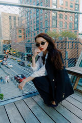 A stylish woman wearing sunglasses posing in a fashionable urban setting