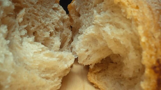 Torn pieces of fresh baguette close-up on dark background. Macro photography of bread placed on wooden tray. Zoom in camera motion. Gourmet and bakery concept. Design for poster, food blog. Pabulum.