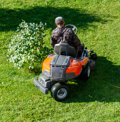 A person operating a lawn mower in a park, cutting the grass.
