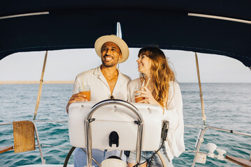 A smiling couple explores the ocean on a sunny day, sipping drinks and enjoying a relaxing boat...
