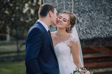 A bride and groom kiss each other in a wedding photo. The bride is wearing a white dress and the...