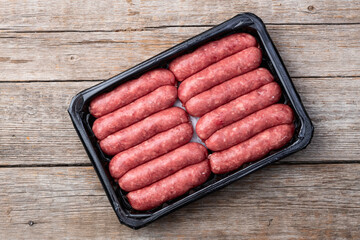 Raw beef sausages with rosemary and tomatoes photography . Top view