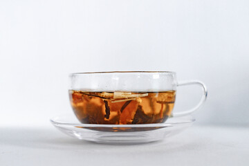 Pouring boiling water from kettle in a glass cup for brewing tea in the kitchen on white table, white background, top view