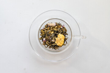 Pouring boiling water from kettle in a glass cup for brewing tea in the kitchen on white table, white background, top view