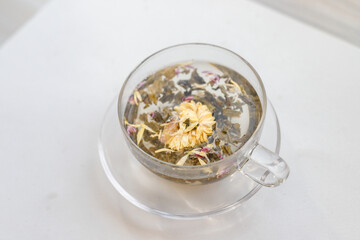 Pouring boiling water from kettle in a glass cup for brewing tea in the kitchen on white table,...