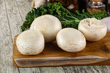 White champignon mushrooms heap over board
