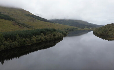 Obraz premium Gorgeous reflection over Loch Lubnaig in Scotland, during a cloudy and misty day. Found this gem during a roadtrip in Scotland.