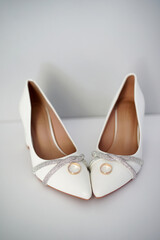 White shoes of the bride and two wedding rings. Wedding ceremony.