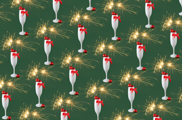 Champagne glass full of christmas decoration, red bow with sparkler on green background. Happy holiday celebration event pattern, New Year Eve or Christmas party concept.