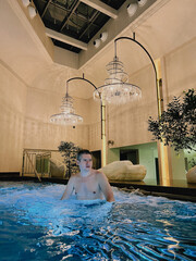 A man is relaxing in an elegant indoor pool at a luxurious resort