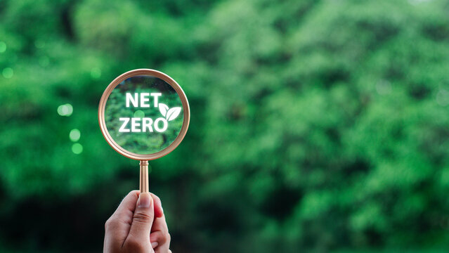 hand holding magnifying glass with CO2 reduction icon inside.A clean and friendly environment without carbon dioxide emissions.carbon credit to limit global warming from climate change.carbon neutral.