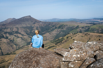 Woman sitting on a mountain peak looking out over a Mountain View in Hogsback, eastern cape