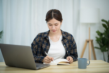 Happy beautiful Asian woman using computer laptop for work online at living room