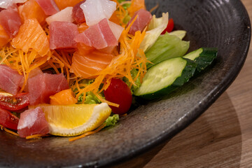 This vibrant image showcases a colorful and refreshing sashimi salad, featuring a mix of fresh, raw fish like salmon and tuna,  tossed with crisp vegetables. 