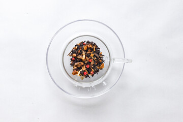 Dried tea leaves in glass cup on white background top view 