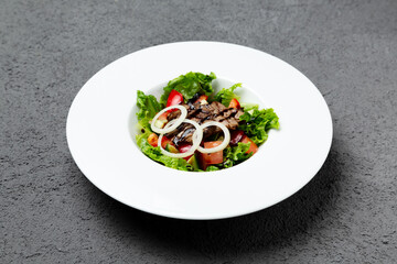 Fresh vegetable salad with roast beef. On a gray background.