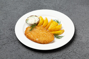 Chicken cutlet with potatoes on a plate. On a gray background. Photo for the menu.