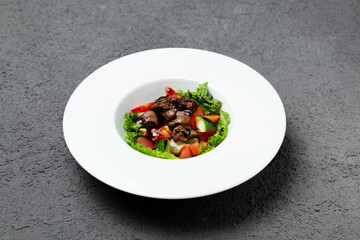 Salad of fresh vegetables and chicken liver. On a gray background. Photo for the menu.