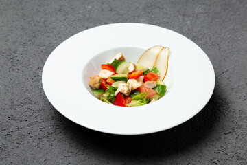 Fresh vegetable salad with chicken and pear. On a gray background. Photo for the menu.