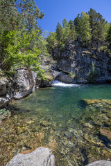 Scenic view of waterfall and lake in a Spanish Pyrenees Mountain in a sunny day. Transparent clear water.