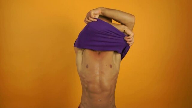 Summer mood. Young athletic man posing in studio on orange background.