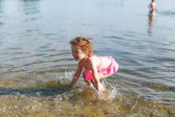Fototapeta premium Cute girl playing on the beach with a sand and water on beach