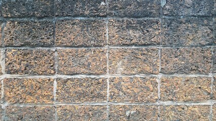 The texture of the old laterite wall is brown. An old stone wall that has aged over time. Photo brick wall. Bricks are laid densely.