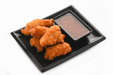 Crispy fried chicken with sauce in black tray on white background.