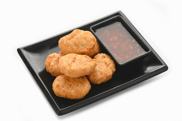 Crispy fried chicken nuggets with sauce in black tray on white background.
